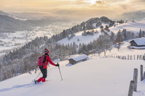 Pretty active senior woman snowshoeing in the Allgäu Alps near Oberstaufen with a view of the