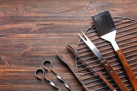 New metallic barbecue utensils wooden background