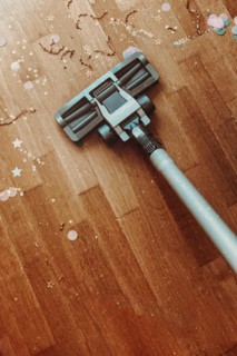 Cleaning apartment after Christmas holidays. Cropped shot of vacuum cleaner nozzle on wooden floor