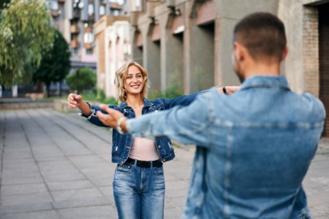Happy meeting of two lovers hugging in the street. Young woman greeting her boyfriend embracing