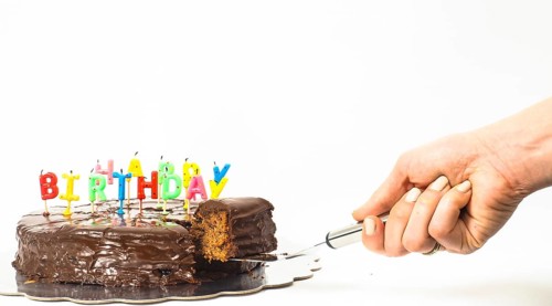 Female person serving a homemade sacher chocolate cake with birthday candles