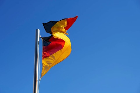 German flag, national flag in strong wind against blue sky