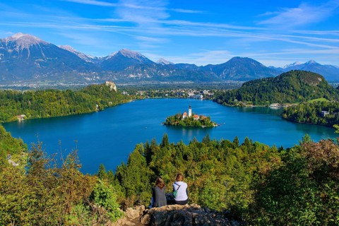 Two people at Osojnica Hill watching the view of Bled Island and Lake Bled, a popular tourist