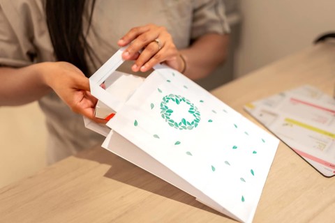 Pharmacist introducing a package of medicine into a paper bag for a client in the counter of the