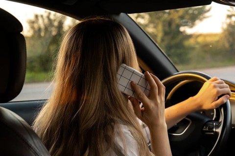 Happy young woman speaking by mobile phone while driving car. Business woman talking phone call in