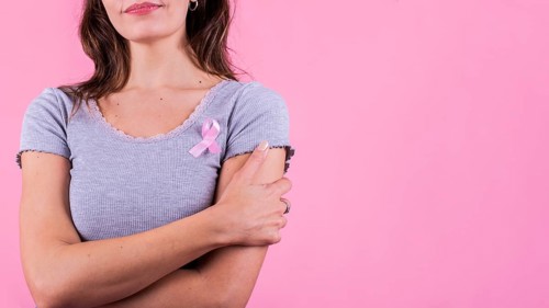 A pink badge ribbon on a woman's chest supporting breast cancer cause