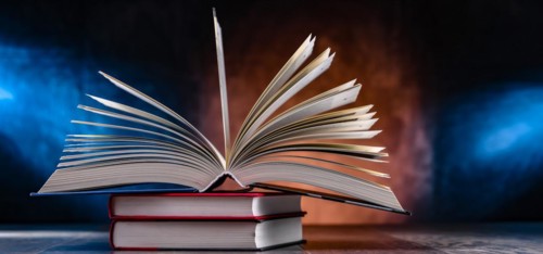 A composition with an open book lying on a stack of other books