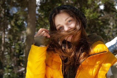 Happy young caucasian woman in a winter down jacket hat and mittens with happiness rejoices