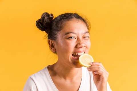 Woman bites slice sour lemon