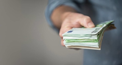 Hand giving a Stack of Euro Bills