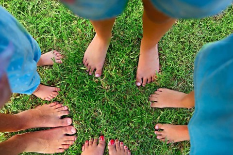 Happy young family spending time outdoor on a summer day. Feet on the grass. Top view