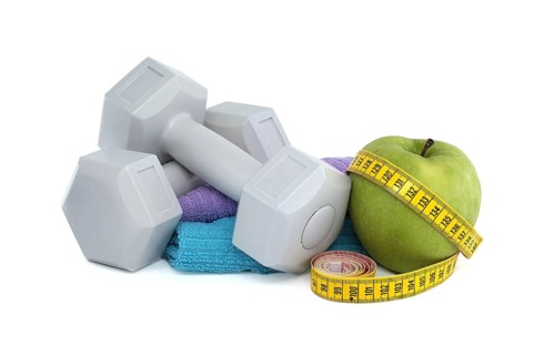 Health and fitness equipment including two gray dumbbells, green apple with a tape measure wrapped