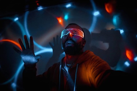 Bearded man wearing futuristic glasses interacting with virtual reality, moving hands and