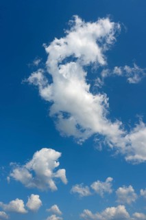 White cumulus clouds ruffled by the strong wind in the blue sky