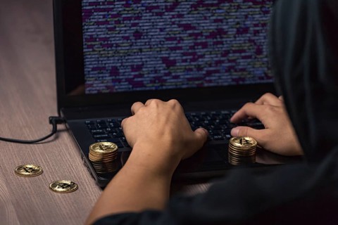 Dangerous hooded hacker on laptop breaks computer security sistem and steal bitcoin cryptocurrency