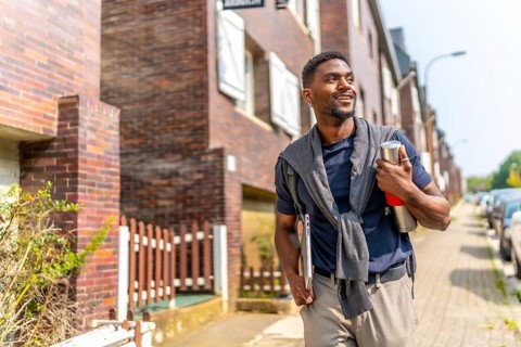 Confident young and handsome african man with casual clothes walking to go to work carrying a