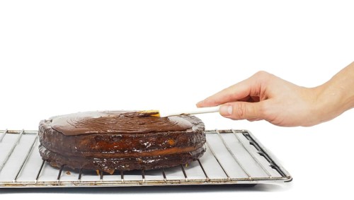 Pastry chef making final touches to a sacher chocolate cake with icing