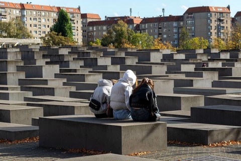 Landmark, Young people sitting on a concrete block at the edge of the Holocaust memorial in autumn,