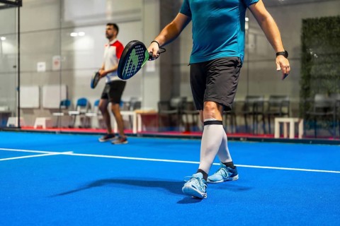 Team of two male mature friends playing paddle tennis in an indoor court