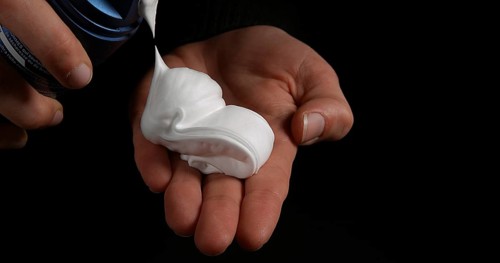 Hand of Woman and shaving foam against Black Background