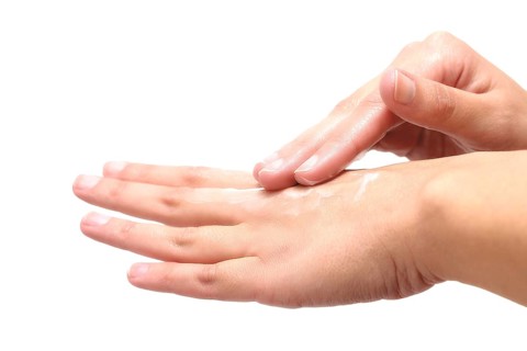 Close-up of female hands while applying moisturizing lotion in order to repair damaged and dry