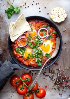 Shakshuka with pita bread in a pan. Middle eastern traditional dish. Fried eggs with tomatoes, bell