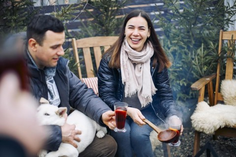 Bonfire party. Joyful young family couple gathering with friends around campfire in winter, happy