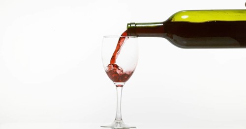 Red Wine being poured into Glass, against White Background