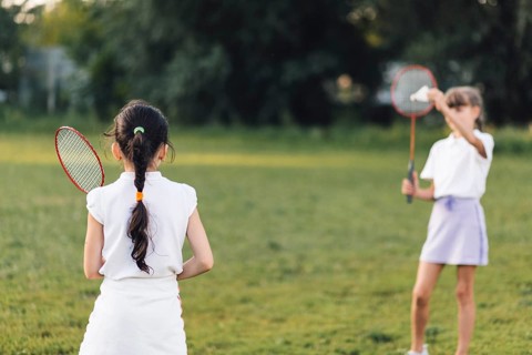 Rear view girl playing badminton with her friend
