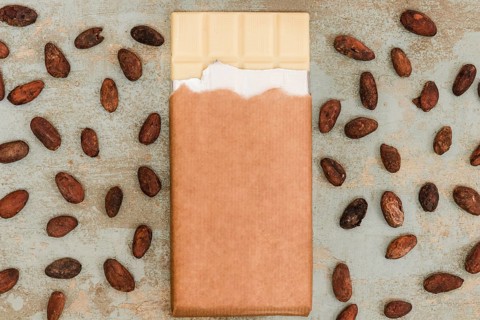 Scattered cocoa beans with white chocolate bar grunge background