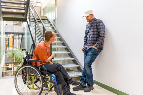 Man with disability talking with a colleague in a modern coworking during a work break