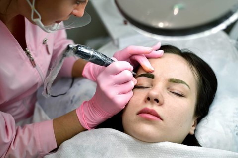 The master does the tattoo on the eyebrows to the girl