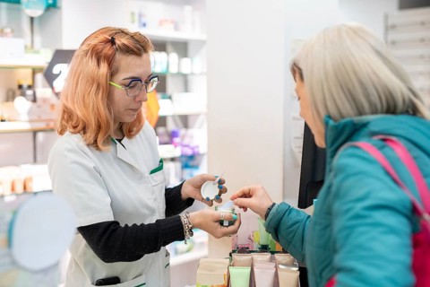 A pharmacist assists a client, showing her essential products. The image reflects the importance of