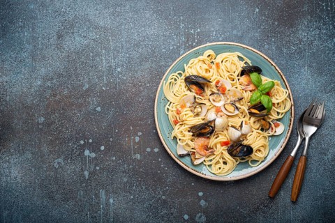 Italian seafood pasta spaghetti with mussels, shrimps, clams in tomato sauce with green basil on