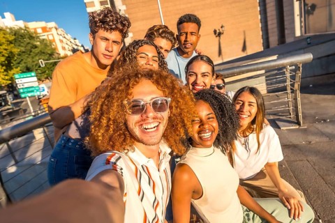 Man with curly hair and multi-ethnic friends taking selfie in the city