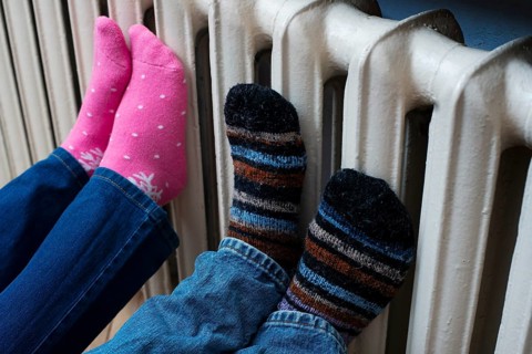 Couple warming up their feet on central heating radiator