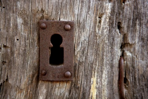 Key hole over aged gray old wood, rusty metal