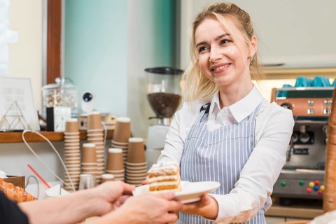Smiling female baker serving pastry cake customer