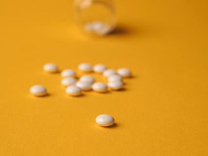 White pills on a yellow background, food supplements, vitamin pills, health care concept