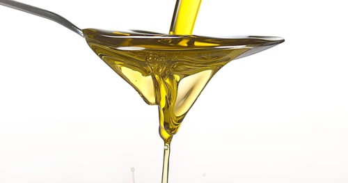 Olive Falling into Olive Oil against White Background