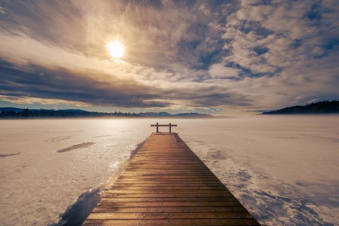 Barred wooden nose-piece on frozen lake in Upper Bavaria with Alps in background in winter with
