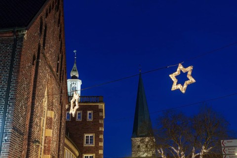 Night landscape of the town with Christmas stars and illuminated church tower against a dark sky,