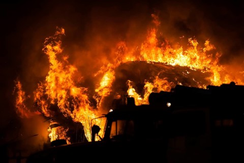Arson or nature disaster, burning fire flame on wooden house roof