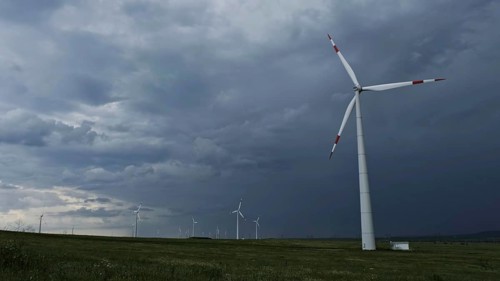 Windmill or wind turbine in rotation to generate electricity energy against the backdrop of a storm