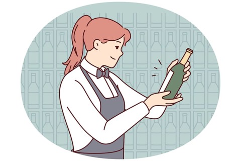 Smiling waitress in apron choosing wine in cellar. Happy female sommelier make choice about drink