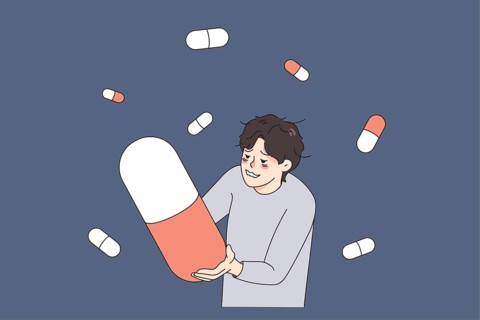 Unhappy stressed man suffer from drug addiction hold huge pill. Upset unhealthy guy struggle with