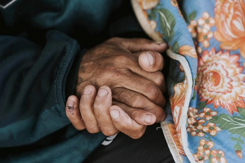 Homeless man holding his hands with blanket