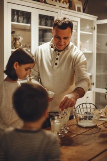 Young family, parent and child cooking homemade cake together in cozy kitchen at home during winter