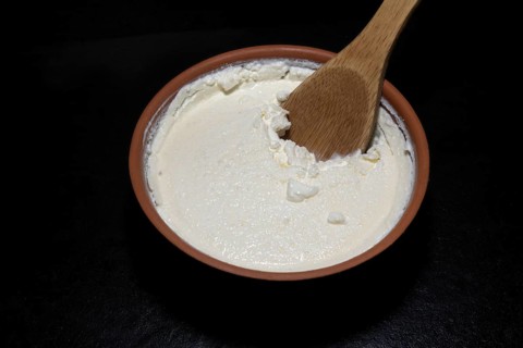 Original Turkish Kaymakli yoghurt matured in a clay bowl, with a wooden spoon, food photography