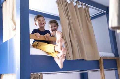 Caucasian little sibling are sitting on the bunk bed and looking to camera with big smile. Concept